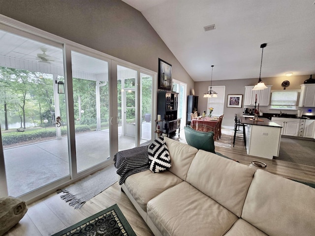 living room featuring lofted ceiling, wood finished floors, visible vents, and an inviting chandelier