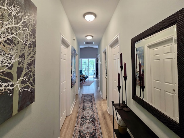 hall featuring light wood-style flooring and visible vents