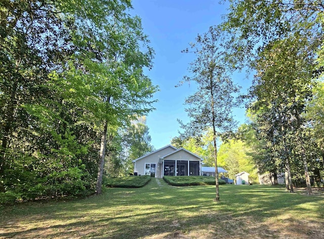 view of yard featuring an outdoor structure, a sunroom, and a storage shed