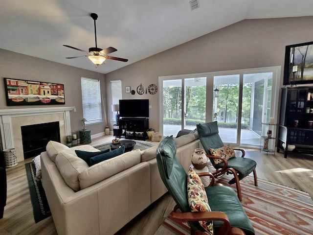 living area featuring a high end fireplace, lofted ceiling, visible vents, and wood finished floors