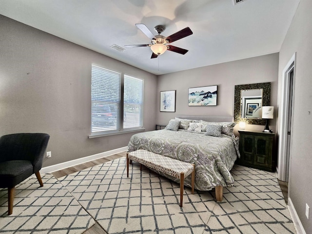 bedroom with visible vents, light wood finished floors, baseboards, and ceiling fan