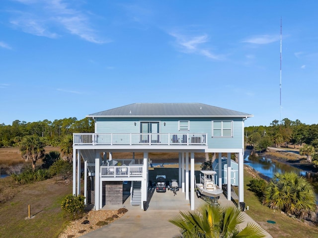 rear view of house featuring a water view, a carport, and a storage shed