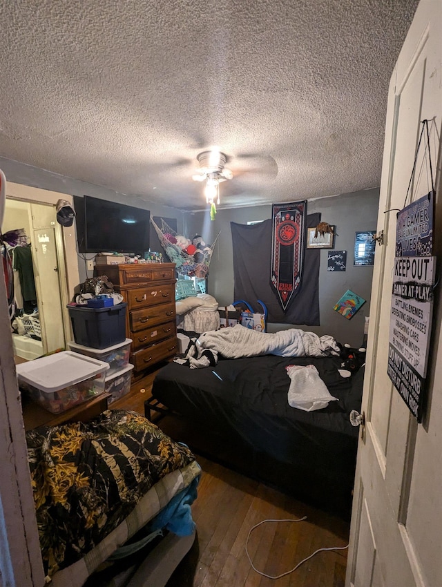 bedroom featuring a textured ceiling, ceiling fan, a closet, and hardwood / wood-style flooring