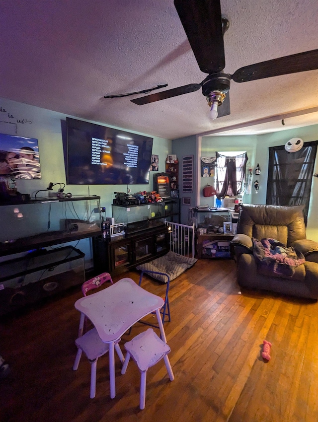 living room featuring ceiling fan, wood-type flooring, and a textured ceiling