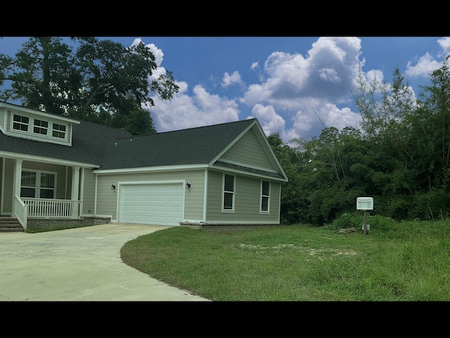 view of front of house featuring a garage, covered porch, and a front yard