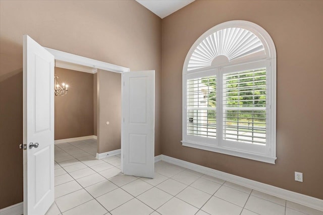 empty room featuring light tile patterned floors and a notable chandelier