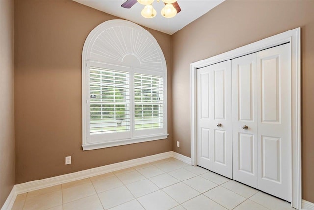 unfurnished bedroom featuring light tile patterned flooring, ceiling fan, and a closet