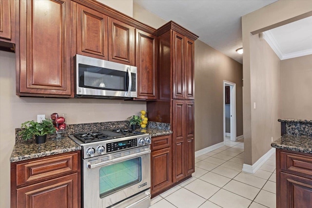 kitchen featuring dark stone counters, light tile patterned floors, crown molding, and stainless steel appliances