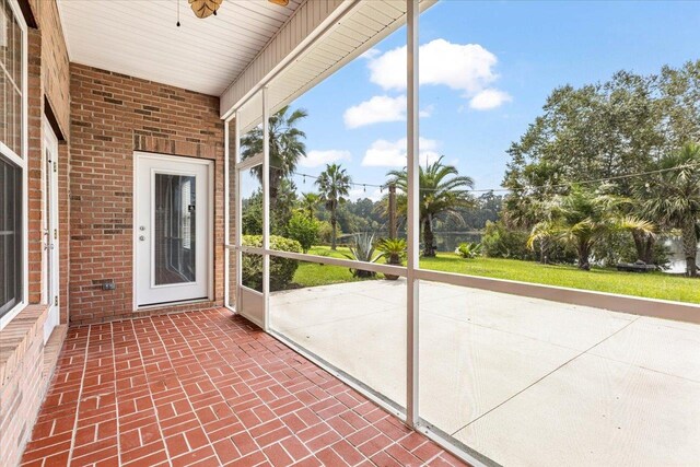 unfurnished sunroom featuring ceiling fan