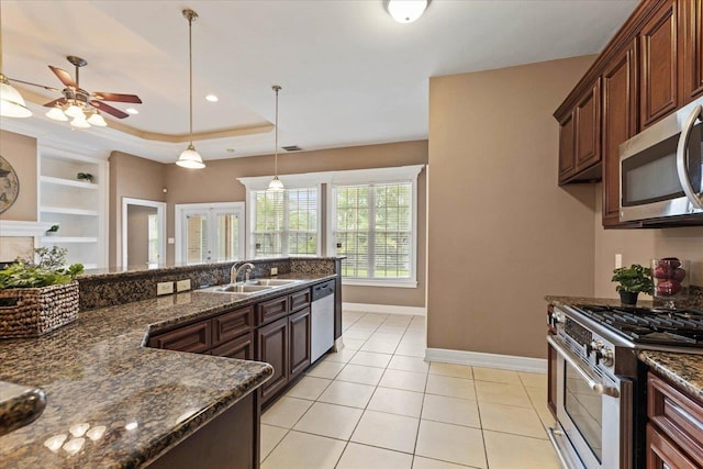 kitchen featuring light tile patterned flooring, stainless steel appliances, decorative light fixtures, sink, and dark stone countertops