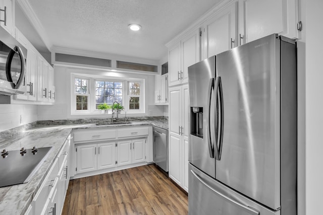 kitchen featuring light stone countertops, white cabinetry, appliances with stainless steel finishes, and dark wood-type flooring