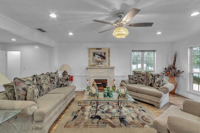 living room with crown molding, ceiling fan, and light wood-type flooring