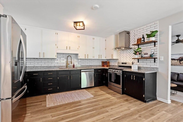 kitchen featuring white cabinetry, sink, wall chimney exhaust hood, stainless steel appliances, and light hardwood / wood-style flooring