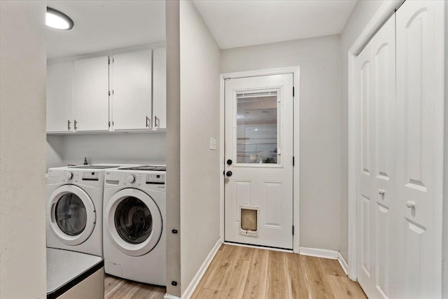 laundry area with washer and dryer, light hardwood / wood-style flooring, and cabinets