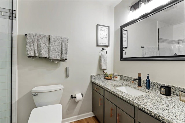 bathroom with vanity, hardwood / wood-style floors, a shower with door, and toilet