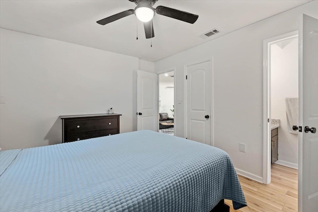 bedroom with ceiling fan, ensuite bathroom, and light wood-type flooring