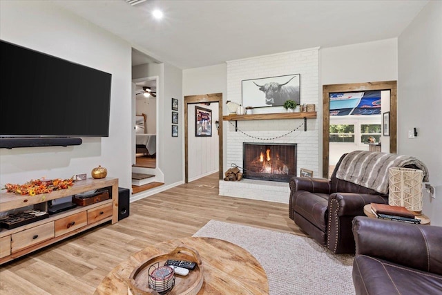 living room featuring a brick fireplace and light hardwood / wood-style flooring