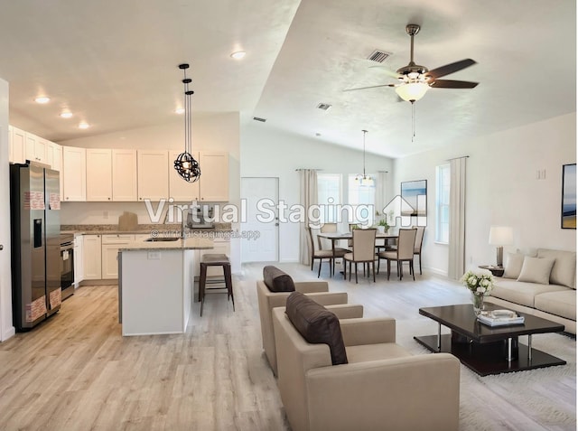 living area with visible vents, baseboards, light wood-type flooring, vaulted ceiling, and a ceiling fan