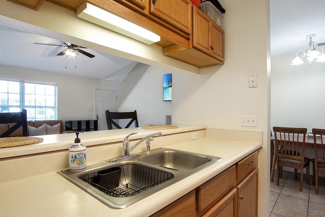 kitchen featuring a sink, brown cabinets, light tile patterned flooring, light countertops, and a ceiling fan