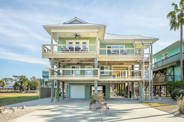 raised beach house featuring a garage, a balcony, a carport, and ceiling fan