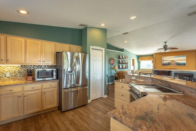 kitchen with light brown cabinetry, vaulted ceiling, wood-type flooring, and appliances with stainless steel finishes