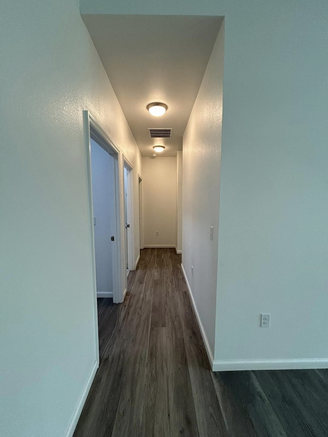 hall featuring dark wood finished floors, baseboards, and visible vents
