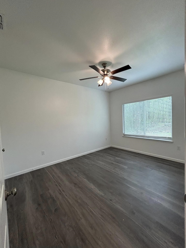 empty room with a ceiling fan, dark wood-type flooring, and baseboards