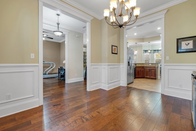 dining room with a wainscoted wall, an inviting chandelier, crown molding, and hardwood / wood-style flooring