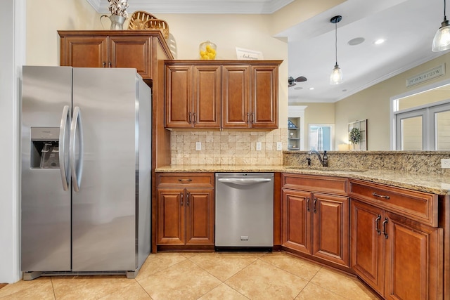 kitchen featuring crown molding, light stone countertops, brown cabinets, appliances with stainless steel finishes, and a sink