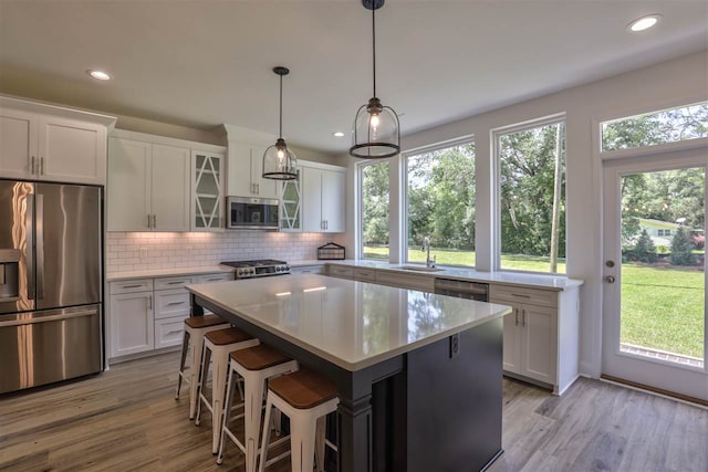 kitchen featuring white cabinetry, light wood-type flooring, appliances with stainless steel finishes, and a center island