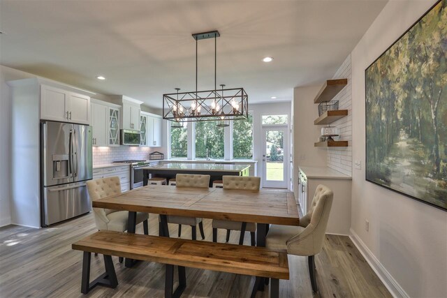 dining space with light wood-type flooring and a notable chandelier