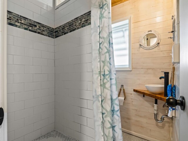 bathroom with walk in shower, wooden walls, and sink