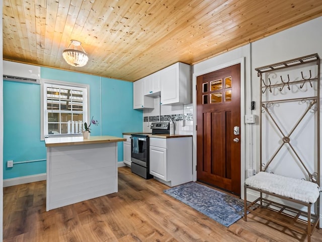 kitchen featuring white cabinetry, stainless steel electric range oven, a wall mounted air conditioner, tasteful backsplash, and light wood-type flooring