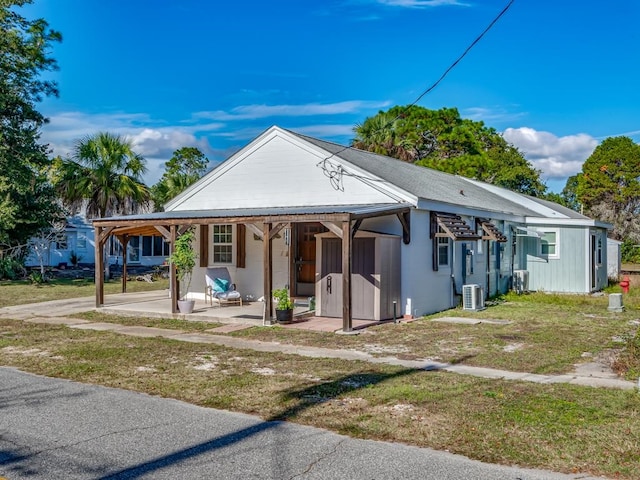 bungalow-style home with a front lawn, a patio, and cooling unit