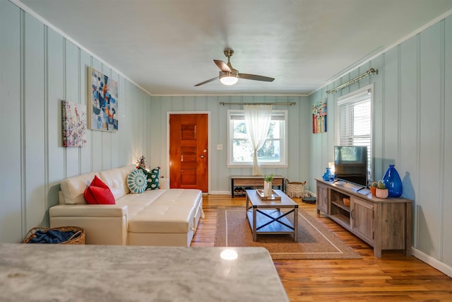 living room featuring hardwood / wood-style floors, crown molding, and ceiling fan