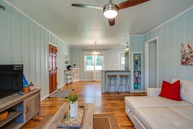 living room with ceiling fan, ornamental molding, and light wood-type flooring