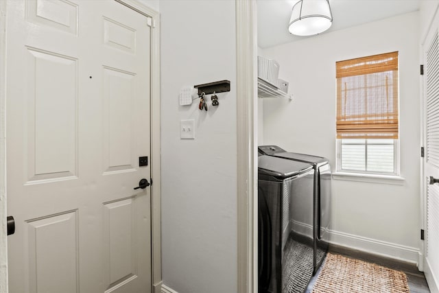 clothes washing area featuring baseboards, separate washer and dryer, and wood finished floors