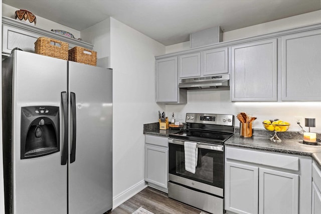 kitchen with stainless steel appliances, under cabinet range hood, wood finished floors, and dark countertops