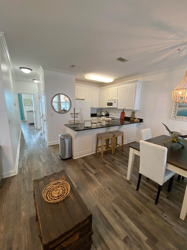 kitchen with white cabinets, dark hardwood / wood-style floors, white appliances, and crown molding