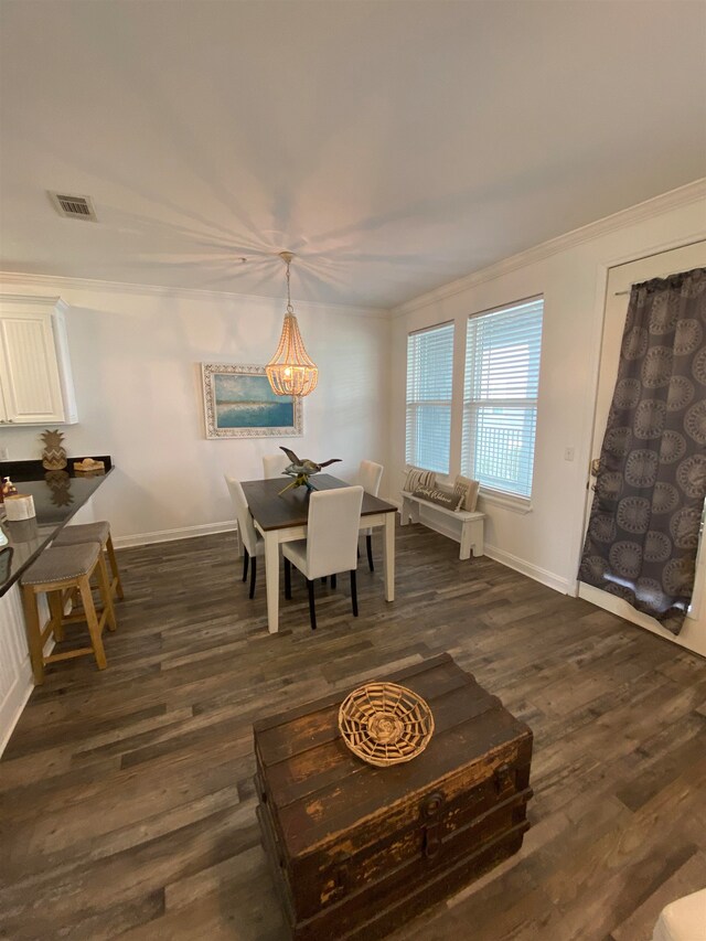 dining area with ornamental molding, dark wood-type flooring, and an inviting chandelier