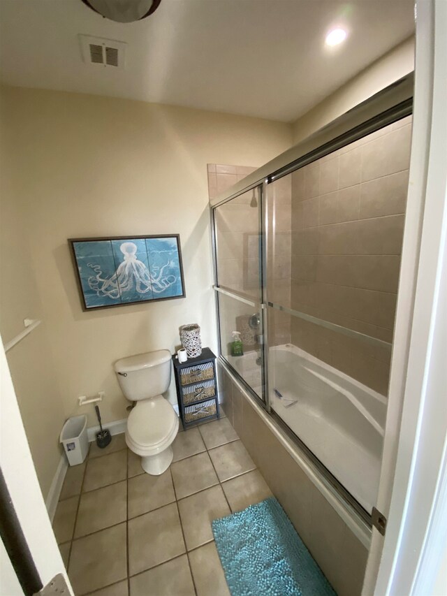 bathroom featuring bath / shower combo with glass door, tile patterned floors, and toilet