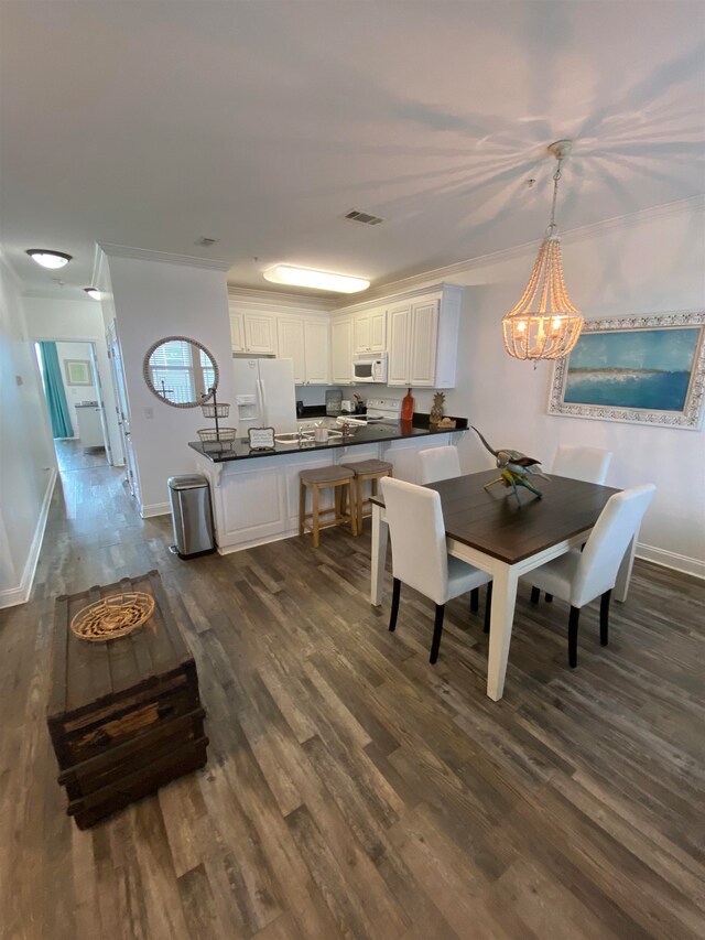 dining area with dark hardwood / wood-style floors, crown molding, and a notable chandelier