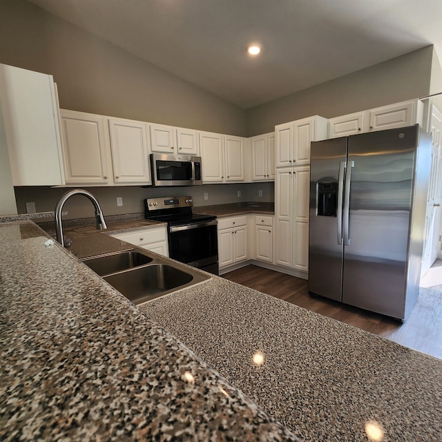 kitchen with white cabinets, appliances with stainless steel finishes, lofted ceiling, and dark wood-type flooring