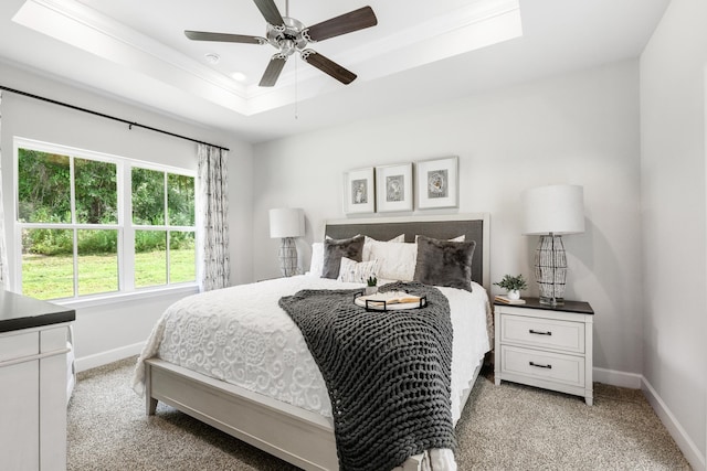 bedroom with a raised ceiling, ceiling fan, and light colored carpet