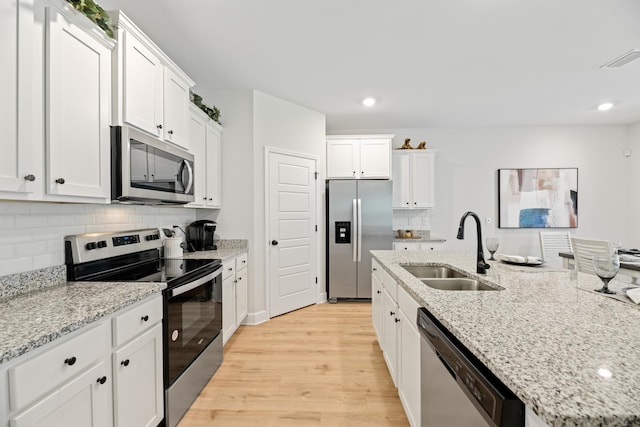 kitchen with stainless steel appliances, white cabinetry, light hardwood / wood-style floors, and sink