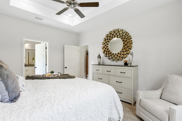 bedroom with connected bathroom, a raised ceiling, ceiling fan, and ornamental molding