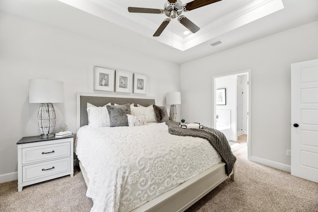 bedroom with ensuite bath, ceiling fan, a raised ceiling, light carpet, and ornamental molding