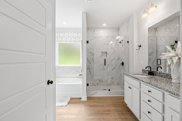 bathroom featuring hardwood / wood-style floors, vanity, and shower with separate bathtub