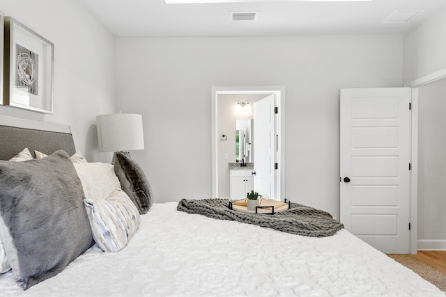 bedroom with ensuite bathroom and light hardwood / wood-style floors