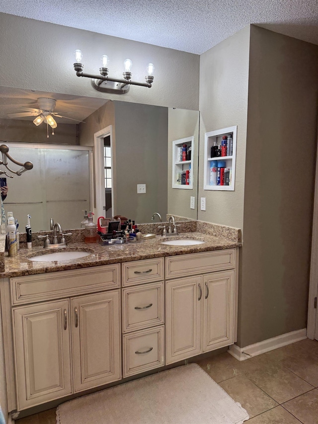 bathroom with a textured ceiling, a shower with shower door, tile patterned floors, vanity, and ceiling fan